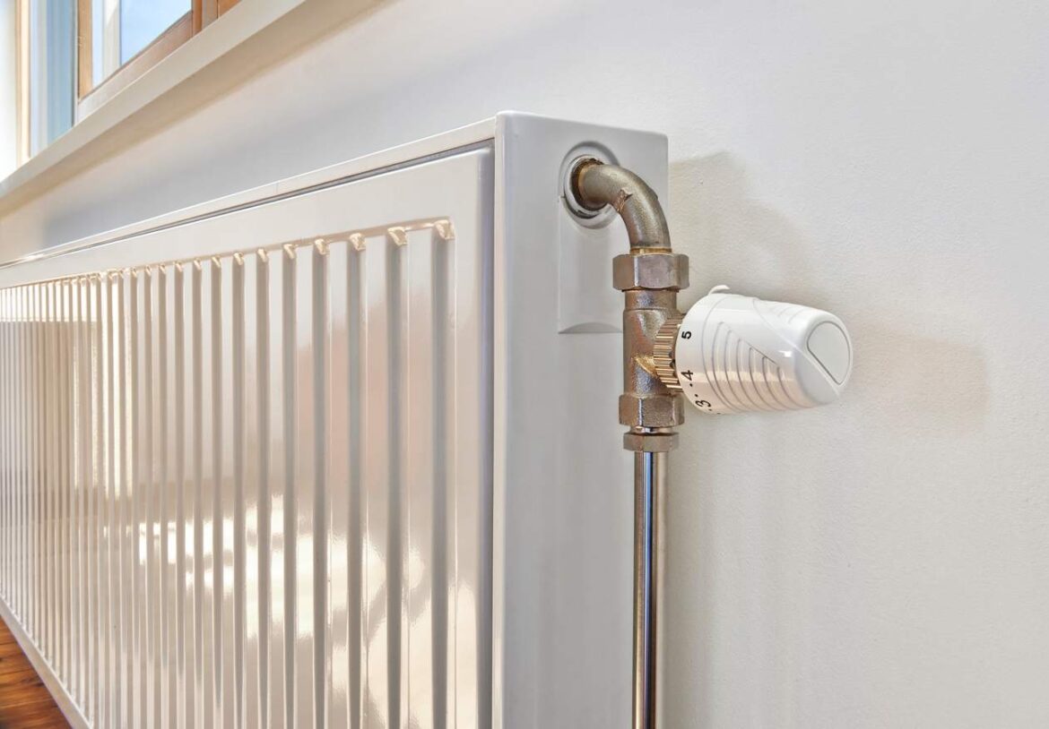 Gros plan sur un radiateur blanc équipé d'un robinet thermostatique pour illustrer la différence chauffage collectif et individuel.