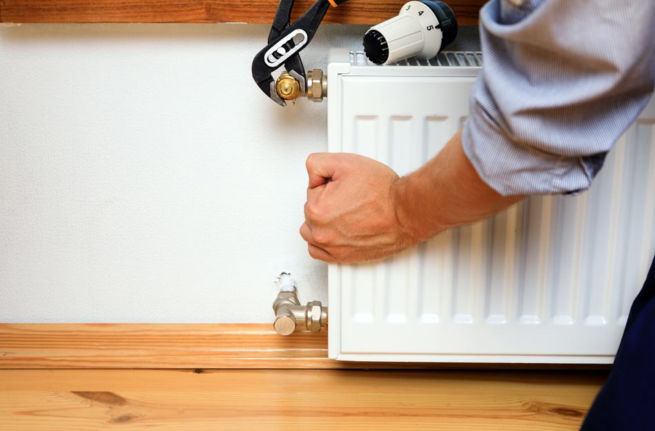 Un technicien règle la vanne d'un radiateur à eau pour éviter les écarts de température avec votre système de chauffage.